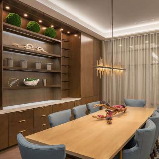 A modern dining room with a wooden table, blue chairs, and elegant lighting.