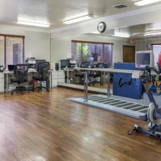 A well-equipped therapy room featuring exercise equipment and a spacious, bright interior.