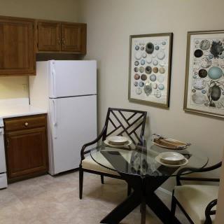 A cozy kitchen and dining area with a glass table set for two.