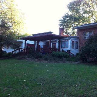 A residential house with a spacious yard and surrounding trees.