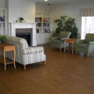 A cozy living room featuring comfortable seating, a fireplace, bookshelves, and decorative plants.