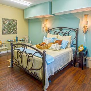 A cozy bedroom with a wrought iron bed, pastel-colored walls, and elegant decor.