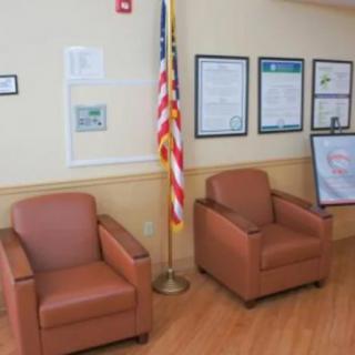 A waiting area with two chairs, an American flag, and posters on the wall.