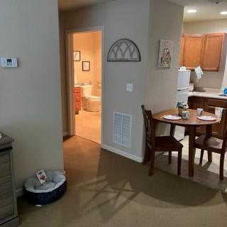 A cozy apartment featuring a dining area with a wooden table and chairs, leading into the kitchen.