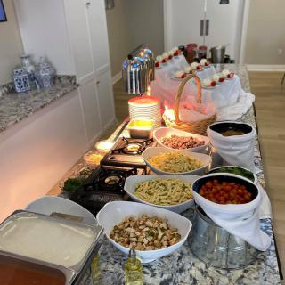 A beautifully arranged buffet featuring pasta and various toppings in a self-serve setting.