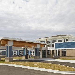 A modern school building with a prominent entrance under a cloudy sky.