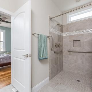 A modern bathroom featuring a spacious walk-in shower with light-colored tiles and a towel hanging on the wall.