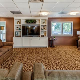 A cozy living room with comfortable sofas, a large television, and decorative shelves.