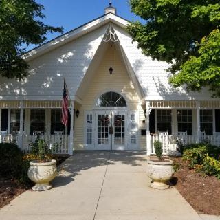 A charming white house with a welcoming entrance and surrounding greenery.