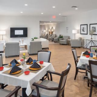 A well-arranged dining area with tables set for a meal, featuring neatly folded napkins and comfortable seating.