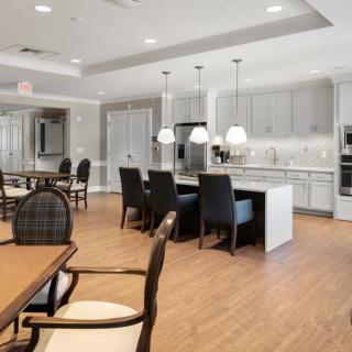 A modern open-concept kitchen and dining area featuring pendant lighting and wood flooring.