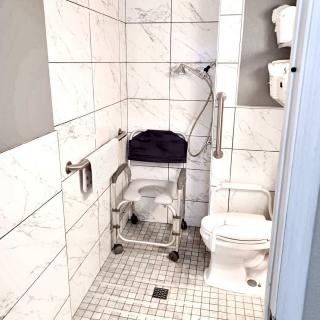A bathroom featuring accessibility equipment such as a wheelchair and grab bars.