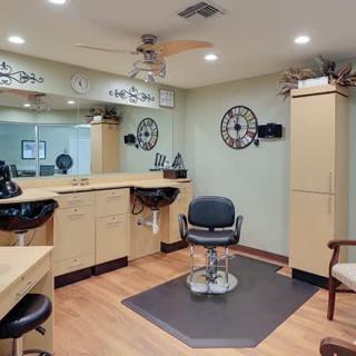 A well-organized hair salon interior featuring a barber chair, large mirrors, and ample cabinetry.