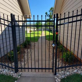 A metal gate leading to a pathway between two residential buildings.
