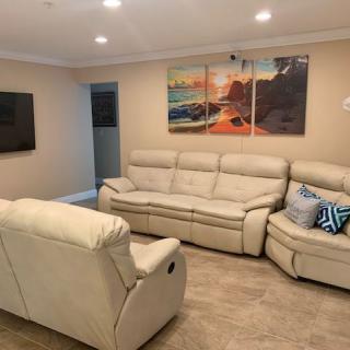 A cozy living room featuring comfortable beige sofas and wall art depicting a scenic sunset.