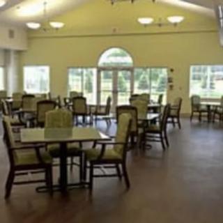 A spacious dining area with multiple tables and chairs, illuminated by natural light through large windows.