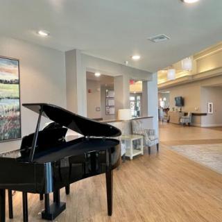 A modern interior space featuring a grand piano, wooden flooring, and contemporary artwork.