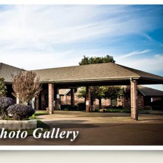 A view of a brick building with a covered driveway and surrounding landscape.