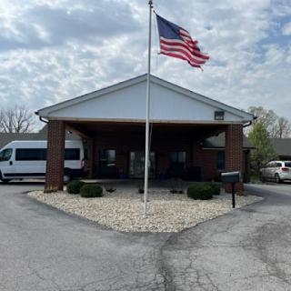 The entrance of a building featuring the American flag and surrounded by vehicles.