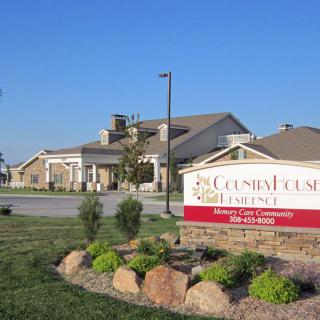 Entrance sign and building surrounded by well-maintained landscaping.