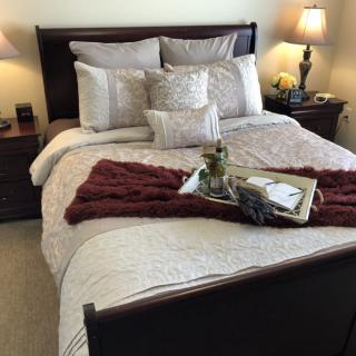A cozy bedroom with a neatly arranged bed, featuring decorative pillows and a stylish tray.