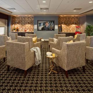 A modern lounge area featuring comfortable seating with patterned chairs and warm lighting.
