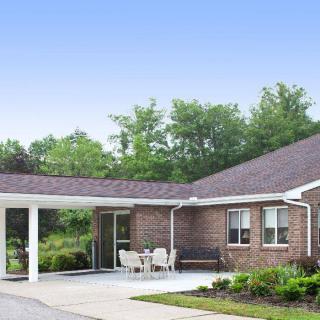 A single-story brick residential building with a covered entrance and surrounding greenery.