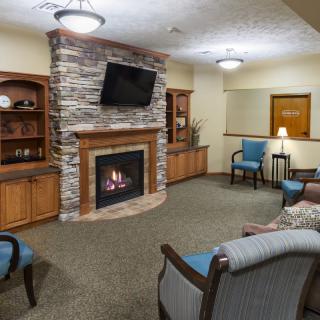 A cozy living room with a fireplace, armchairs, and a wall-mounted television.