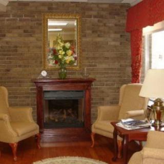 A cozy living room with a brick fireplace, armchairs, and a decorative mirror.