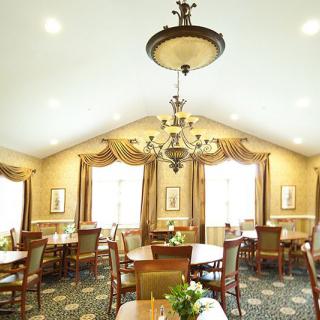 An elegant dining room featuring a large chandelier, multiple tables and chairs, and richly decorated curtains.
