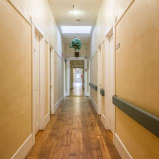 A long, well-lit hallway with wooden floors and multiple doors on either side.