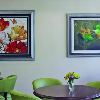 A cozy seating area with green chairs and decorative paintings on the wall.