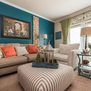 A cozy and stylish living room featuring a colorful palette with a striped ottoman as the focal point.