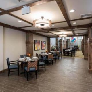 A modern dining area with wooden accents, featuring tables, chairs, and decorative artwork.