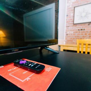 A TV with a remote control resting on a table in a cozy living room.