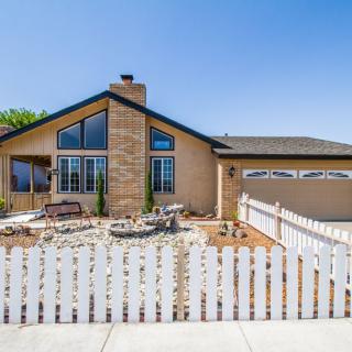 A single-story house with a white picket fence and a front yard.