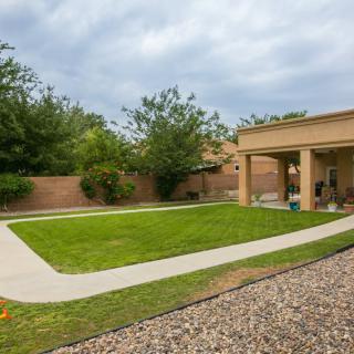 A neatly maintained backyard with a lush lawn, patio area, and surrounding garden.