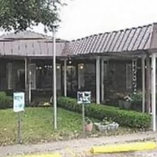 Exterior view of a commercial building with a metal roof and landscaped surroundings.