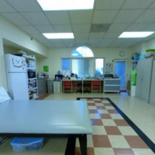 An office workspace with desks and computers under bright fluorescent lighting.