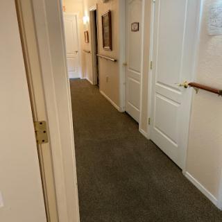 A view of a well-lit hallway featuring carpeted floors and multiple doors leading to different rooms.