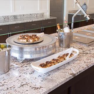 A kitchen countertop with serving dishes, featuring desserts and a champagne bucket.