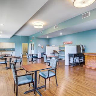 A spacious dining area featuring tables and chairs, with a modern design and blue walls.