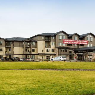 Exterior view of a hotel building with a well-maintained grass lawn in the foreground.