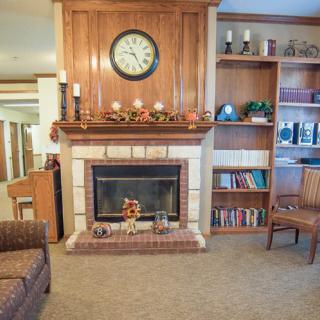 A cozy living room with a fireplace, clock, and bookshelves.