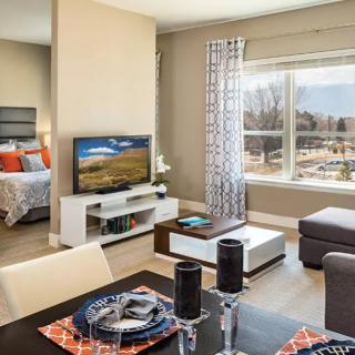 A modern open-concept living space with a dining area and an adjacent bedroom, featuring stylish decor and ample natural light.