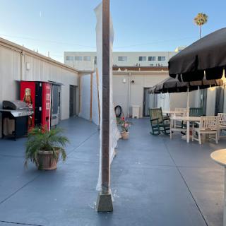 An outdoor patio area featuring a grill, seating arrangements, and a vending machine.