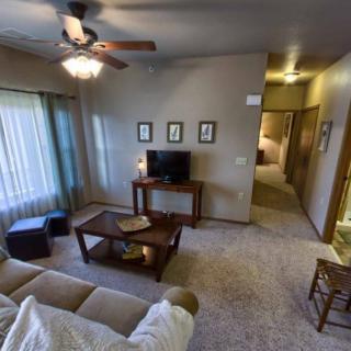 A cozy living room with a sofa, coffee table, and television under a ceiling fan.