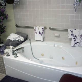 A cozy bathroom featuring a large bathtub with floral towels and decorative elements.