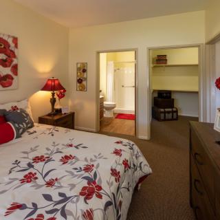 A cozy bedroom with floral decor, featuring a view into a bathroom and walk-in closet.