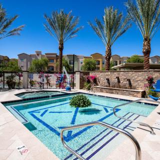 A luxurious outdoor pool surrounded by palm trees and vibrant landscaping on a sunny day.